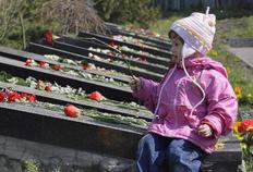 Ένα κοριτσάκι αφήνει ένα λουλούδι στο μνήμα των θυμάτων του ατυχήματος του Τσερνομπίλ.